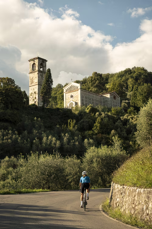 Female cyclist riding towards a church near Lucca, Italy.
