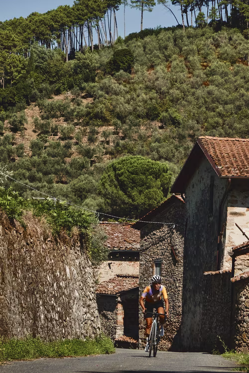 Female cyclist pedalling through Sant'Andrea di Compito, Lucca.