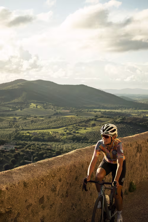 Female cyclist riding through the town of Capalbio, Tuscany.