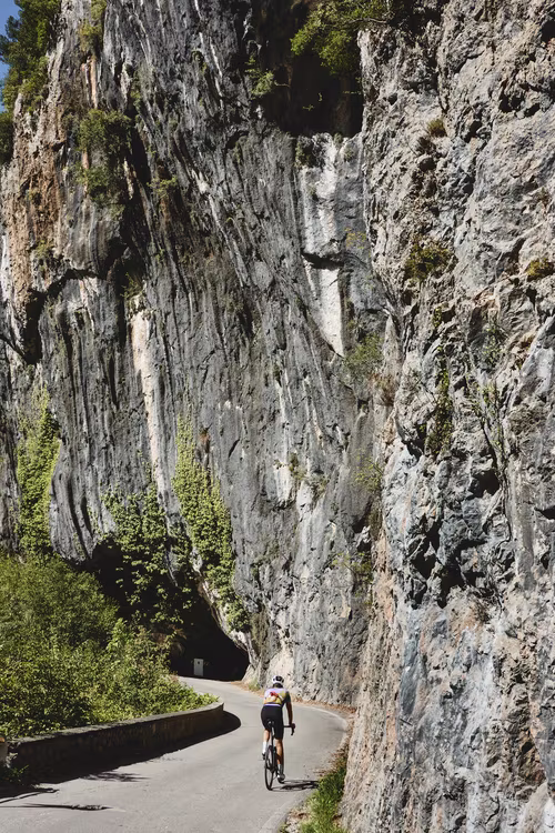 Male cyclist riding next to a stone cliff in Garfagnana, Tuscany.