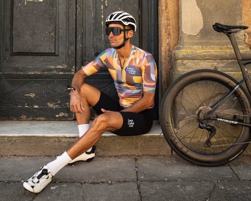 Male cyclist sitting on a step with his bike leaning next to him.