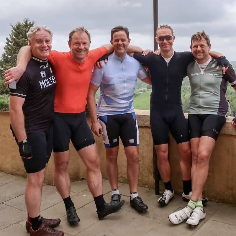 Five standing men wearing cycling clothes.